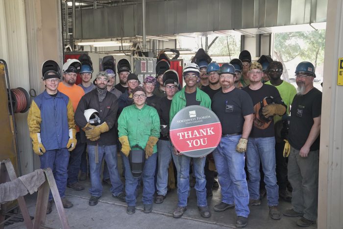 Welding students hold "Thank you" sign